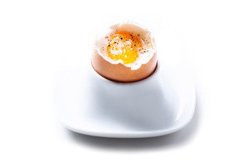 Boiled egg with salt and pepper over a dish and white background