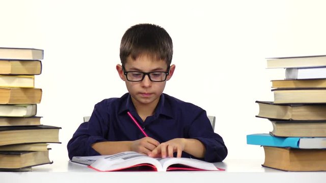 Boy sits at the table leafing through the book. White background