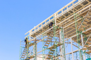 Construction workers working on scaffolding, Man Working on the Working at height with blue sky at construction site