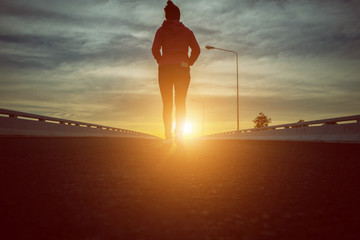 silhouette woman walking on the street at sunset.