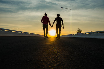 Closeup of loving couple holding hands while walking at sunset