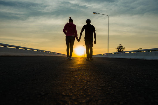 Closeup of loving couple holding hands while walking at sunset