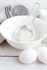 bowl with flour, eggs and milk on a white background closeup