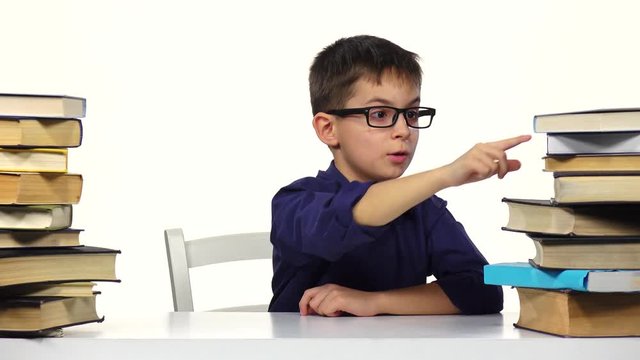 Boy sits at a table and reading a book. White background