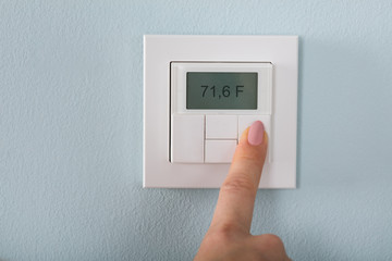 Person Setting The Thermostat