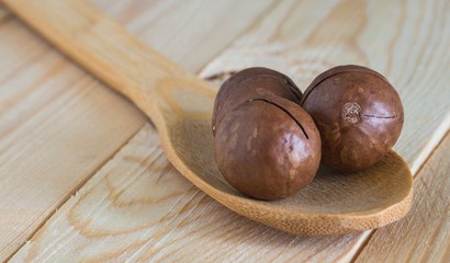 macadamia nuts in wooden spoon on wooden table