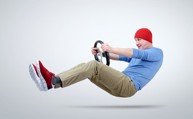 Man in red cap drives a car with a steering wheel
