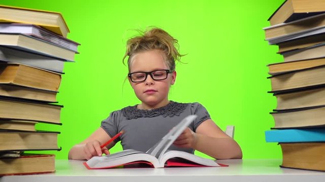 Girl sitting and leafing through the book. Green screen. Slow motion