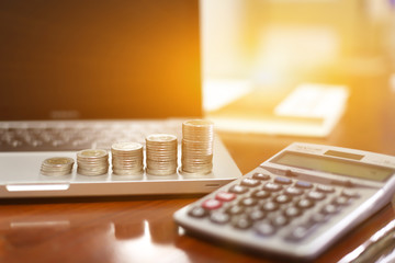 Concept business finance save money, Coins stack on wood table with blurred calculator background , stack of money, rows of coins for finance and banking concept, selective focus
