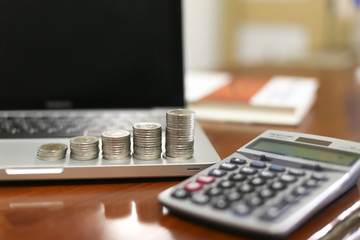 Concept business finance save money, Coins stack on wood table with blurred calculator background , stack of money, rows of coins for finance and banking concept, selective focus