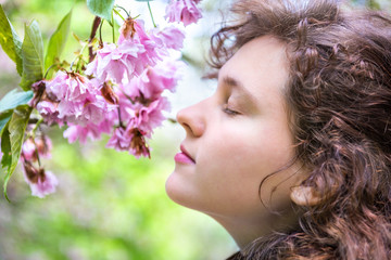 Naklejka premium Side profile of young woman smelling cherry blossoms