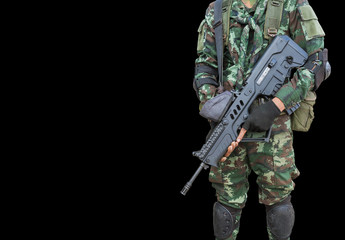 soldier in uniform holding automatic assault rifle on black background