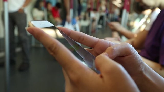 Asian woman sit down in train checks her phone, writting SMS text with friends using Line, social network, as she waits for arrive her stop station in Hong Kong-Dan