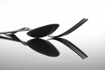 Fork and spoon on glossy table surface
