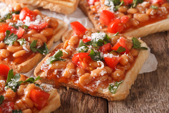 toasts with beans in a tomato sauce, cheese and herbs macro. horizontal