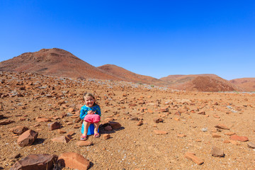 Mädchen sitzt auf Töpchen in der Wildnis, Damaraland, Region Kunene