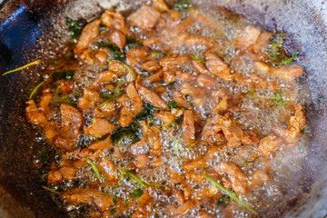 Frying pork pieces in a pan with hot oil