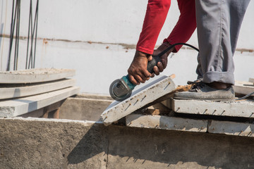 Builder worker with grinder machine cutting concreate floor at construction site