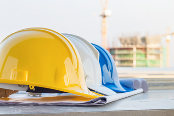 The safety helmet and the blueprint at construction site with crane background