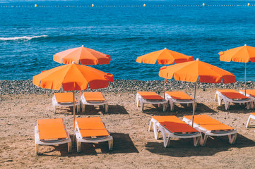 Orange sunshades and deckchairs against ocean