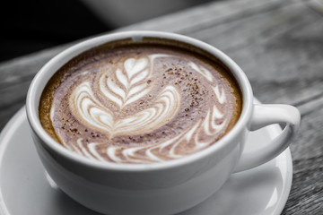Latte art coffee on natural wood table.