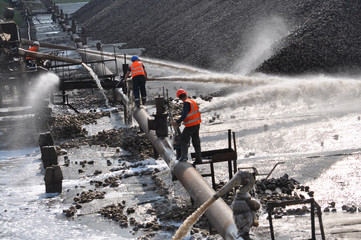 Workers sugar factory with water on piles of sugar beets served raw material for further processing...