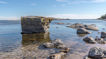 Fototapeta na wymiar Solid rock standing on calm waters