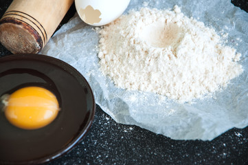 Flour, eggs, yolk on a black working space. Preparation for cooking concept.