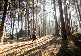 Girl wearing sportswear and running in forest at mountain