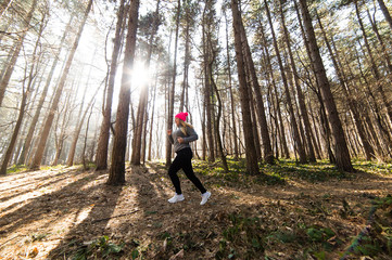Girl wearing sportswear and running in forest at mountain