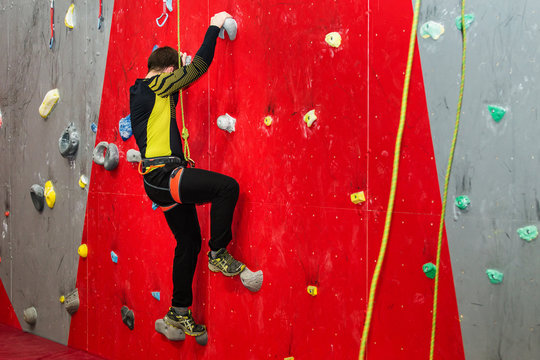 young caucasian man training at artificial rock climbing indoors