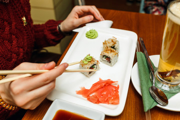 Woman eating sushi rolls with chopsticks in a restaurant