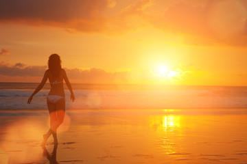 Silhouette of woman on the sunset. Colorful dawn over the sea. Nature beauty. Carefree woman enjoying the sunset on the beach. Happy lifestyle