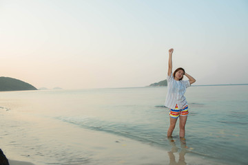 Happy woman standing arms outstretched  and enjoy life on the beach at Sea