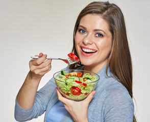 Young smiling woman holding glass bowl with vegetable salad. Isolated portrait.