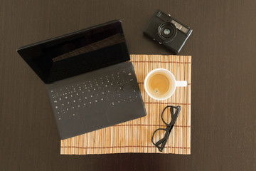 top view of a workspace with coffee, laptop and sunglasses