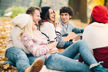 Friends having picnic outdoor. Man playing guitar.