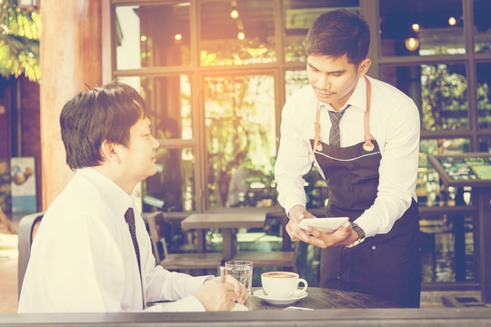 waiter with touchpad make order from businessman at table