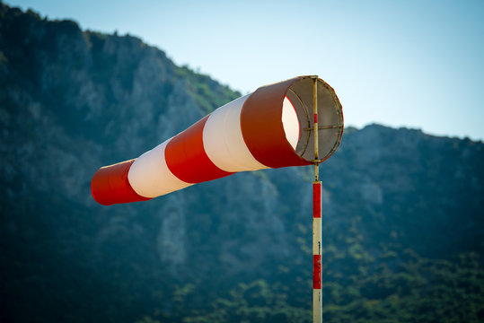 Horizontally flying windsock (wind vane) due to high wind. Blue sky and high mountains in the background.