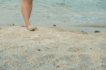 Woman legs on the sand beach and sea water.