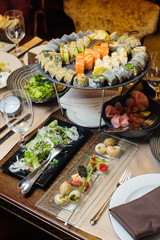 Appetizers on the table - sushi, salad and snails.Selective focus/Various sushi rolls on plate,salad and snails with berries pieces