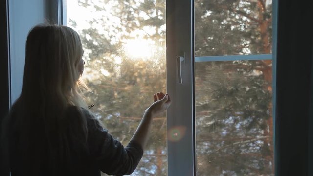 A woman opens a window and breathing fresh frosty air