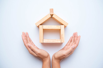 Hand arranging wood block as house. Real estate business concept.