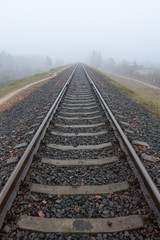 Fototapeta na wymiar railroad goes into the mist. gray misty autumn morning.