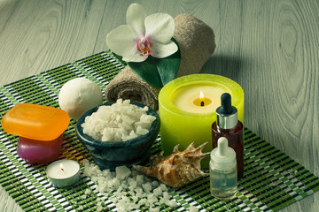 Fototapeta na wymiar Spa products on wooden background Orchid flower, bowl with sea salt, seashell, bottles, soap, candles and towel