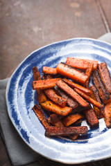 Roasted carrots on a blue plate on a brown table copy space