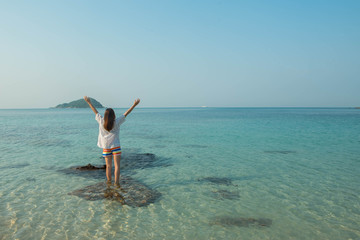 Happy woman standing arms outstretched on the beach at Sea