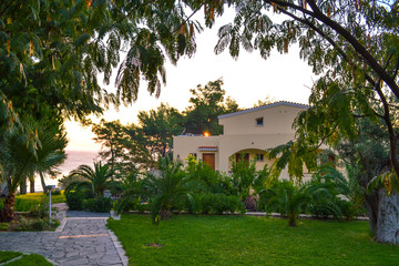 Fototapeta na wymiar The house by the sea among green plants. Greek hotel Aegean Melathron, Greece - September, 2013.