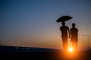 Silhouettes of couple against umbrella the sunset.