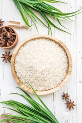 rice in wooden plate and anise on white wooden background. Rice and spices in ecological container. Set for cooking. Set for spa.